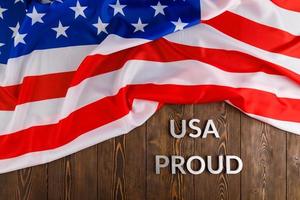 words USA proud laid with silver metal letters on brown wooden surface with flag of United States of America photo