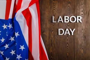 words labor day laid with silver metal letters on wooden surface with crumpled USA flag on left side photo