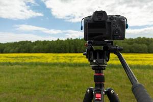 cámara sin espejo profesional moderna en trípode disparando campo amarillo en trípode, primer plano foto