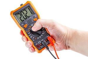 digit 2021 on lcd screen of digital electrical multimeter in left hand, isolated on white background photo