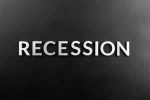 the word recession laid with white brushed metal letters on flat black surface photo