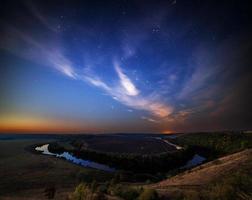 paisaje ribereño de verano en la noche estrellada con nubes moradas foto