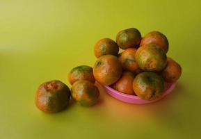 varias naranjas en un plato rosa sobre un fondo amarillo 01 foto