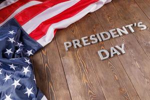 words presitdents day laid with silver letters on wooden surface near US flag photo