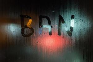 the word ban written on night wet window glass close-up with bokeh background photo