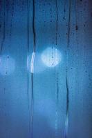 an abstract background of night wet window glass with smudges in blue tone gamma photo
