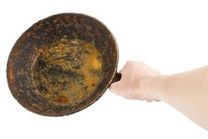 bare caucasian hand holding empty old cast iron frying pan photo