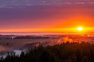 foggy flatland riverside at golden summer sunrise photo