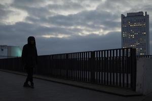 Guy on street in city in evening. Young man in black jacket. photo