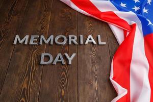 the words memorial day laid with silver metal letters on wooden board surface with crumpled usa flag photo