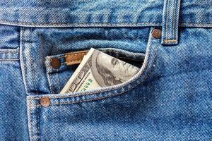 un billete de cien dólares que sobresale del bolsillo delantero de los jeans foto