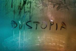 the word dystopia handwritten on wet window glass surface photo