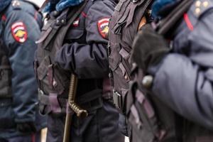 oficiales de policía en uniforme negro con chalecos antibalas - vista de cerca en guantes negros. foto