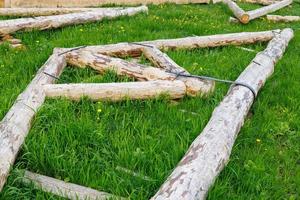 forged steel stripe connection of wooden log beams for roof support girder framework laid on green grass at summer day photo