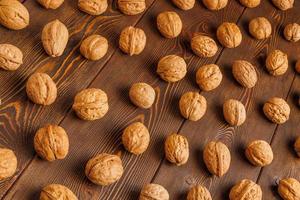 many walnuts with shells evenly spread out on brown wooden surface photo