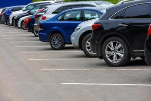 row of different color cars on asphalt parking lot at cloudy summer day photo