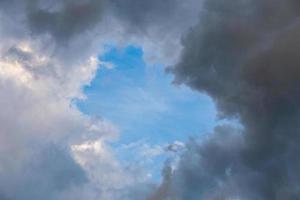 natural blue sky window in clouds, round gap in solid summer clouds photo