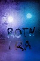 the words roth ira handwritten on night wet window glass surface photo