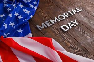 the words memorial day laid with silver metal letters on wooden board surface with crumpled usa flag photo