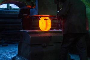 close-up picture of hot steel manual forging process with big mechanical hammer machine photo