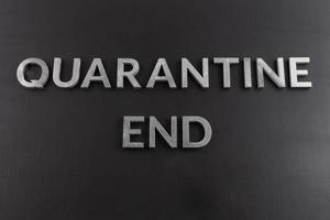 the words quarantine end laid with silver metal letters on matte back flat surface directly above in flat lay perspective photo