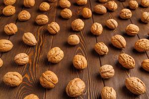 many walnuts with shells evenly spread out on brown wooden surface photo