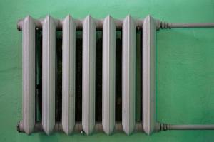 gray painted cast iron water radiator on green wall photo