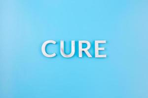 the word cure laid with thick aluminium letters on blue background photo