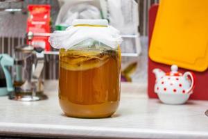 té de kombucha casero en tarro de cristal en la mesa de la cocina foto