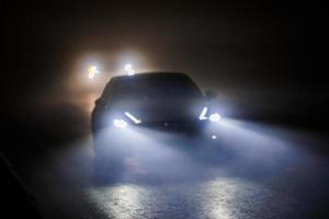 two blurred cars moving on empty night foggy road photo