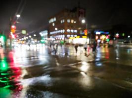 defocused night rain city street view with cars crossing road photo
