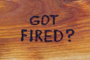 question got fired handwritten with hand woodburner on flat brown wood surface photo