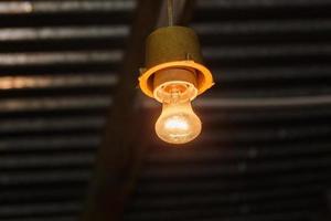 Vieja y sucia lámpara de bombilla incandescente de tungsteno de vacío de vidrio desnudo bajo techo foto