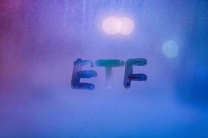 abbreviation word etf - exchange traded funds - handwritten on foggy glass window at night with neon blue back street light photo