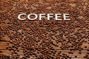 word coffee laid with silver letters on board surface covered with coffee beans photo