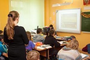 Tula, Russia, January 18, 2013, Beautiful young teacher woman standing among sitting students in a middle school class. photo