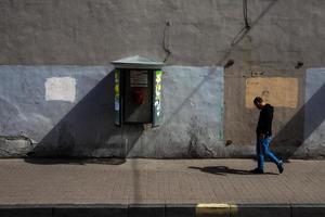san petersburgo, rusia, 13 de junio de 2014 hombre adulto con auriculares caminando de lado cerca de la pared pintada con call-box. foto