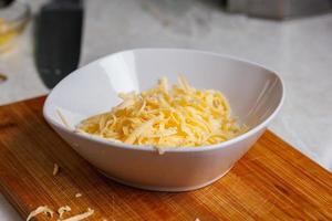 grated cheese in white ceramic bowl close-up view with selective focus photo