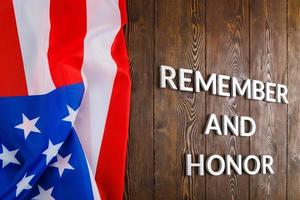 words remember and honor laid with silver metal letters on wooden background with USA flag on the left side photo