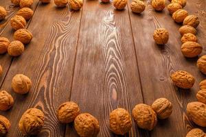 muchas nueces con cáscaras esparcidas en forma de marco rectangular sobre una superficie de madera marrón foto