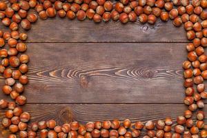 rectangular frame of many hazelnuts with shells on brown wooden surface photo