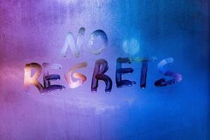 words no regrets hand written on purple-blue night foggy window glass photo