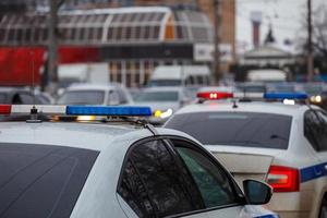 two police cars lights in city street at winter day with cars traffic in blurry background photo