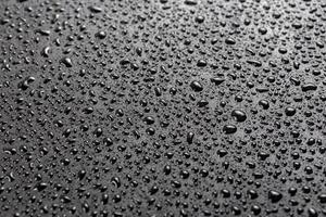 water drops on abstract flat black hydrophobic surface macro background with selective focus photo