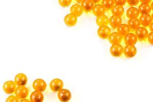 orange spherical ball capsules of fish oil selective focus isolated on white background photo