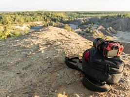 cámara profesional y mochila fotográfica en la cima de la colina durante el día de verano foto