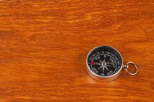 Simple compass on brown wood surface photo