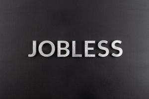 the word jobless laid with white scratched metal letters on flat black surface photo