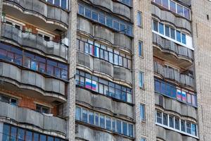 large russian apartment building balcony windows with russian tricolor flags photo