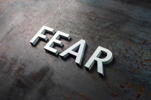 the word fear laid with silver letters on raw rusted steel sheet surface in diagonal slanted composition photo